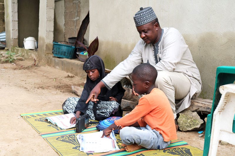 Father-supporting-children-to-listen-to-radio-lesson-1 