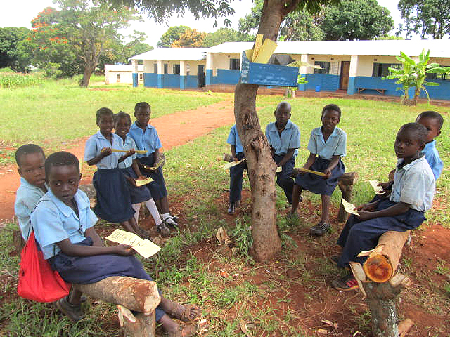 Around the reading tree, children at Chiparamba Basic School can access reading materials and practice sounding out vowels and consonants together.