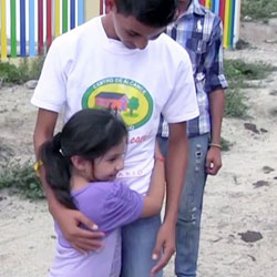 Honduran girl hugging Honduran teenage boy.