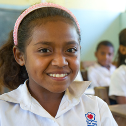 Girl smiling in East Timor classroom.