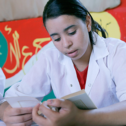 Fille marocaine lisant un livre en classe.