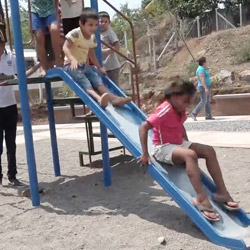 Niños salvadoreños jugando en tobogán.