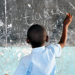 Zambian boy learning to write on chalk board.