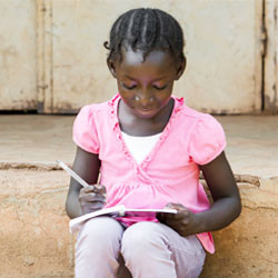 Mozambican girl reading and writing steps.