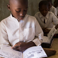 Nigerian boy reading book in classroom.