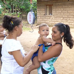 Honduran mother weighing child.