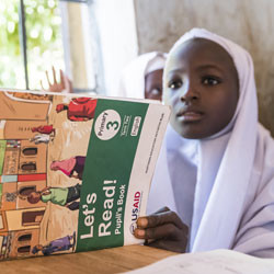 Nigerian girl reading book in classroom.
