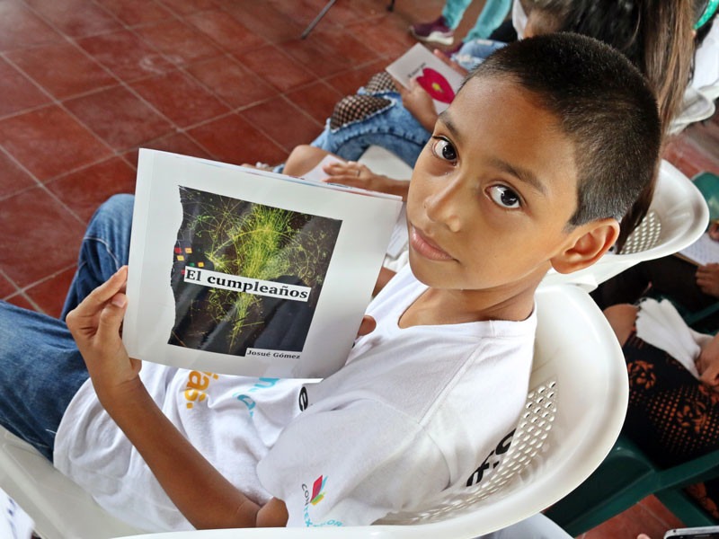 A young boy holds his book.