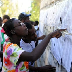 A Haitian woman consults a voter list.
