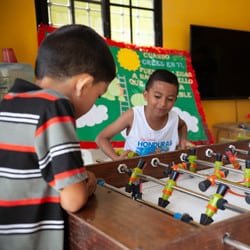Two young boys play foosball.