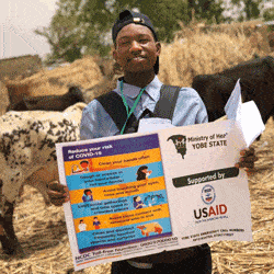 A volunteer holds a poster with COVID-19 prevention tips in Yobe State, Nigeria.