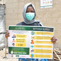 A volunteer holds up an educational poster about COVID-19 in Nigeria.