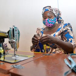 A Nigerian woman sews a face mask.