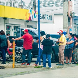 A line of people at a bank wearing masks
