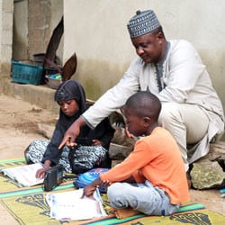 A family works in their school books and follows along on the radio.