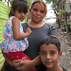 A young woman in Honduras walks with two children.