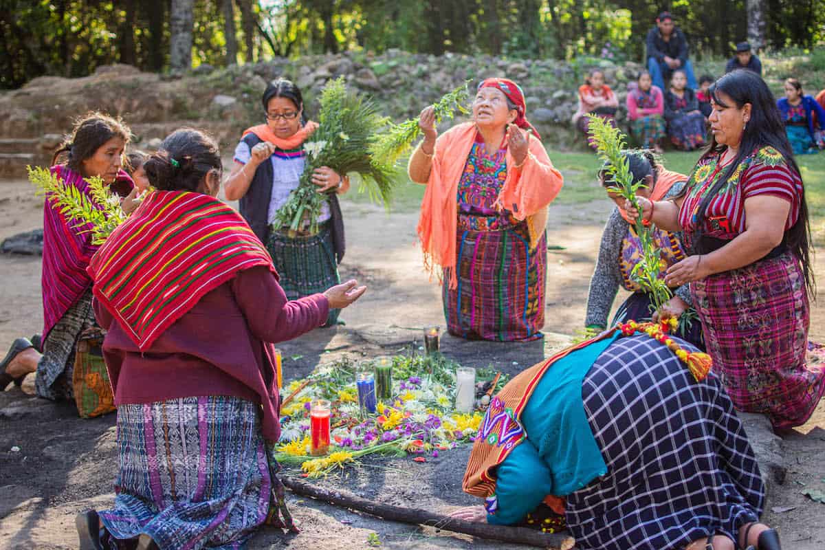 Women kneeling on the ground to perform a ceremony